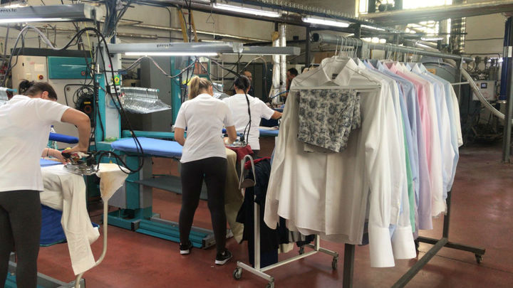 Empleados realizando labores de planchado en la tintorería