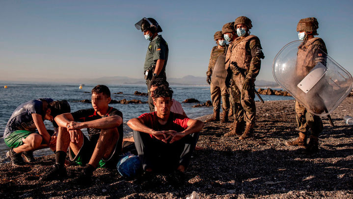 Miembros del ejército observan a un grupo de inmigrantes menores a su llegada a la playa de El Tarajal en Ceuta / EFE