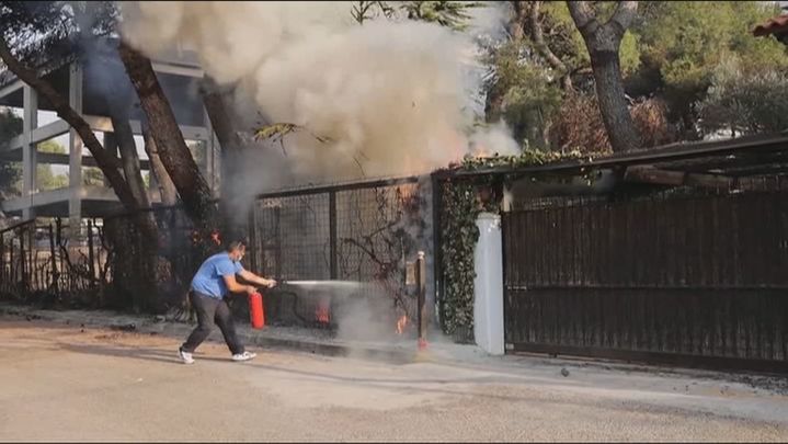 Un hombre trata de apagar las llamas que amenazan su casa en Atenas / TELEMADRID