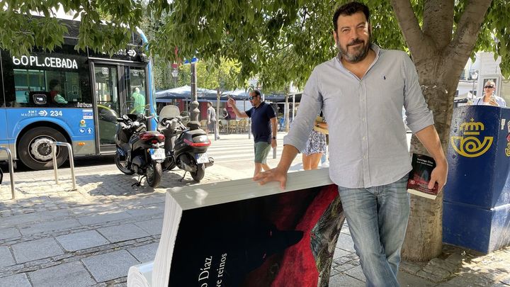 Sergio Díaz posa con su novela junto a su banco 'libro' / Estefanía Esteban