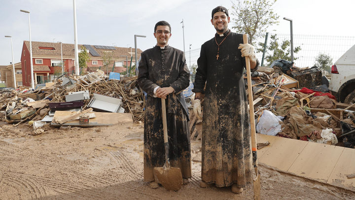 Dos sacerdotes limpian el lodo / EFE