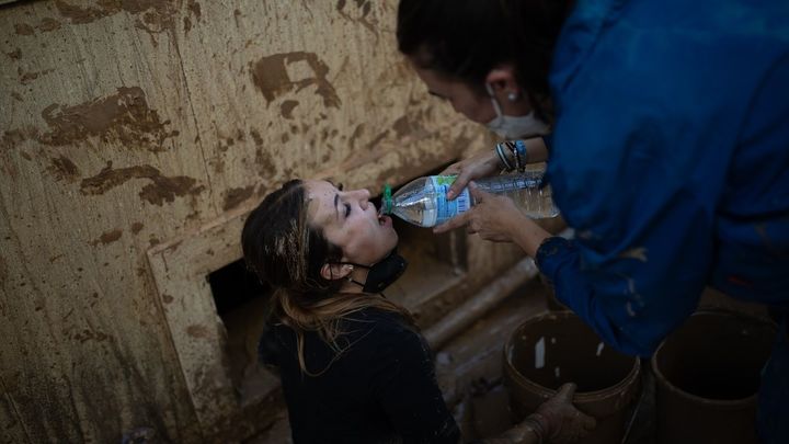 Una mujer bebe agua embotellada mientras limpia el barro tras la DANA / EUROPA PRESS