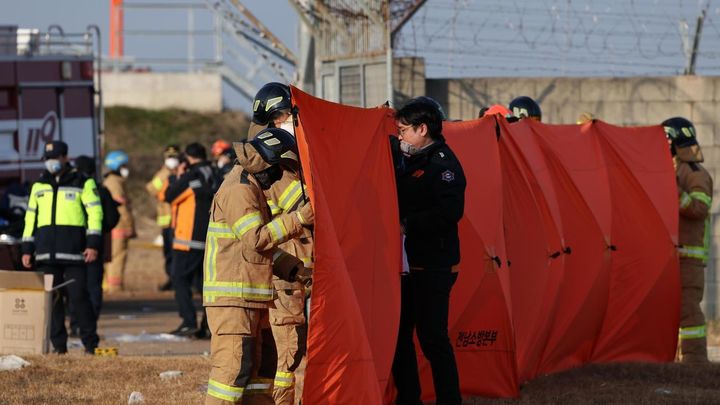 Los bomberos despliegan una mampara plegable durante las operaciones de rescate en el aeropuerto internacional de Muan / EFE